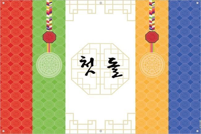 Little Seouls Traditional Korean First Birthday Celebration Banner in red, green, yellow, and blue vinyl with Korean text '첫 돌'.