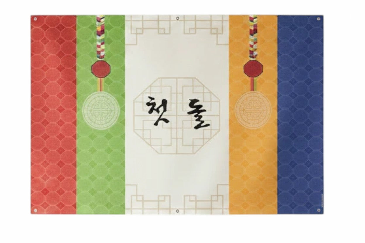 Little Seouls Traditional Korean First Birthday Celebration Banner in vinyl, featuring red, green, yellow, and blue bands with Korean text '첫 돌' for Doljanchi.